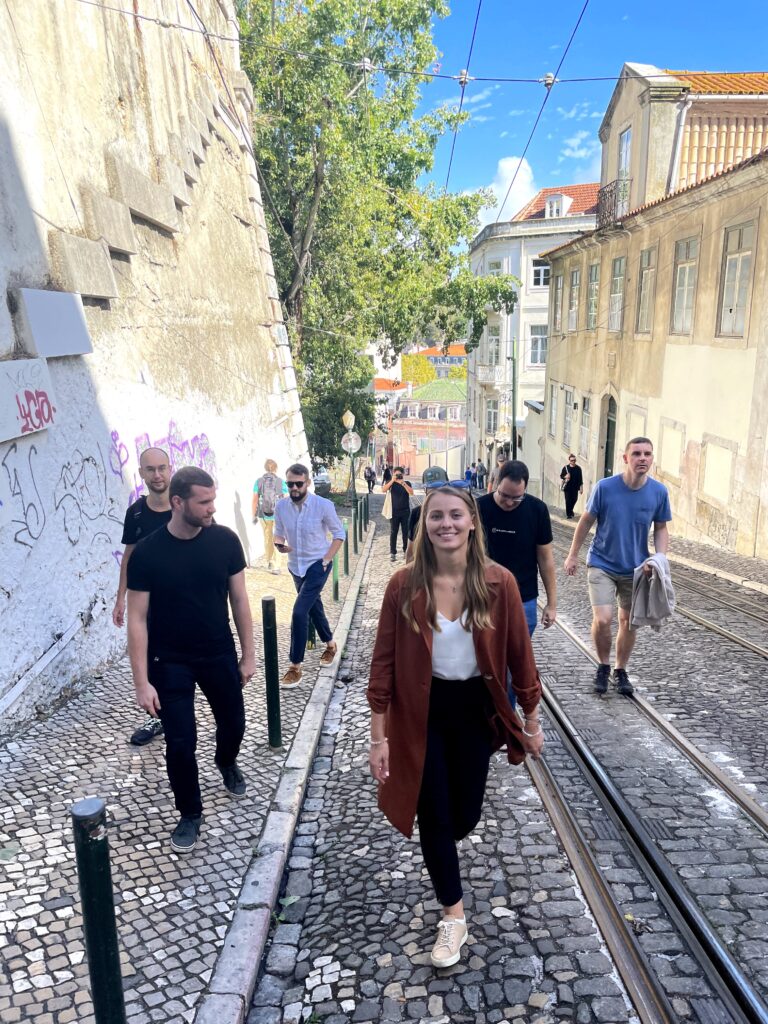 Seven members of the primehammer team walk up a cobblestone street in Lisbon.